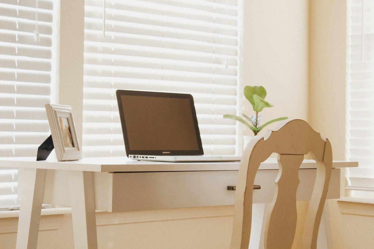 Escritorio con computadora y lámpara junto a una ventana